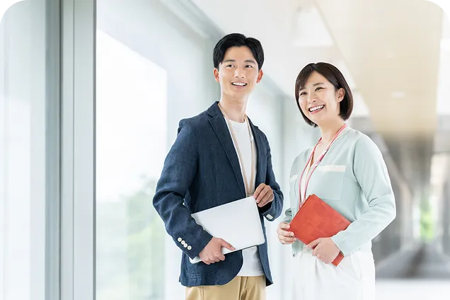 笑顔を向けるスーツ姿の男女